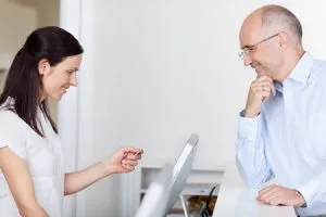 woman helping a patient with his insurance information